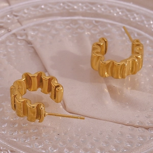 Vue macro des boucles d'oreilles en acier doré 18K au design froissé et ondulé unique