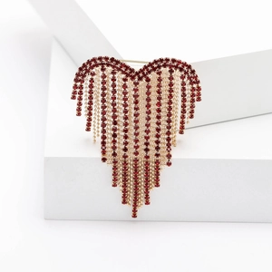 Detail of luxury heart tassel brooch with red rhinestones and gold chain links