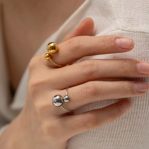 Detailed view of gold and silver minimalist open rings with polished double spheres