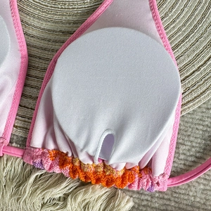 Detail view of pink bikini top with removable white padded cups and colorful pleated trim