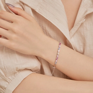 Close-up of colorful heart-shaped cubic zirconia bracelet on woman's wrist with silver chain