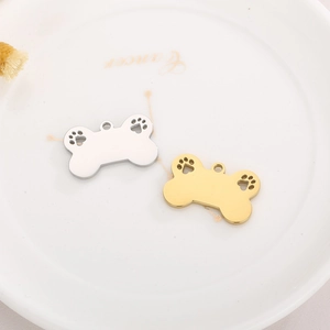 Macro shot of bone-shaped pet ID tags in gold and silver with hollow paw print detail