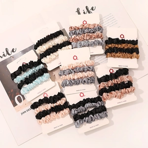 Three-piece set of satin silk scrunchies in various colors on white display cards