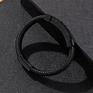 Detail of black braided leather men's bracelet with textured metal clasp and wave pattern