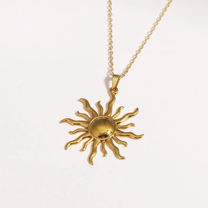 Dettaglio macro di una collana con ciondolo a sole dorato in acciaio al titanio lucido