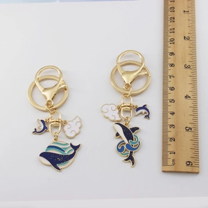 Detailed size view of enamel whale and cloud keychains with ruler for measurement