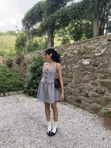 Detail of checkered halter dress featuring front buttons and a ruffled hem in a garden