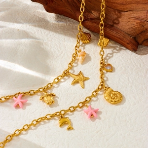 Golden ocean theme necklace featuring sea star, turtle, and shell charms on driftwood