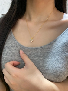 Detail of elegant three-petal pearl flower pendant on a thin gold chain for women