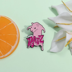 Pink cartoon enamel pin with RATZ text on green background with orange slice and flower