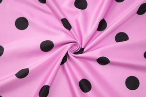 Gros plan du tissu rose à pois noirs montrant la texture douce et la matière pliée