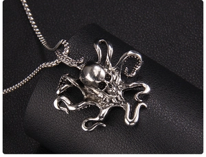 Close-up of a silver punk octopus skull pendant on a dark textured background