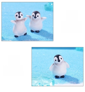 Close-up of mini resin penguin figurines with detailed craftsmanship on blue sand base
