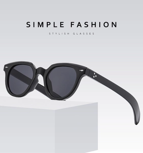 Detail of black oval sunglasses with silver star rivets on minimalist white pedestal