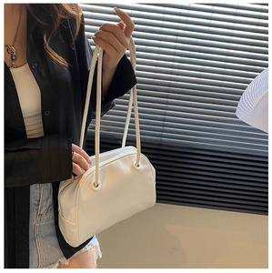 Detailed view of a white minimalist PU leather tote bag worn by a model in a studio setting