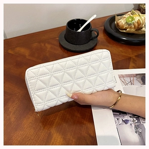 White quilted faux leather wallet held over a coffee table for a stylish lifestyle look
