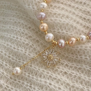 Elegant freshwater pearl bracelet with zircon flower charm on soft knit background