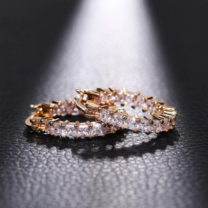 Detailed view of rose gold huggie hoop earrings with square-cut cubic zirconia on leather