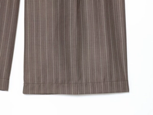 Gros plan détaillé montrant les coutures de l'ourlet et la texture rayée du pantalon brun