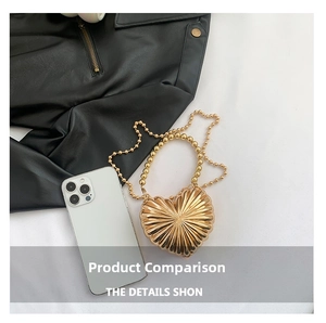 Detail of gold heart-shaped metal mini bag with radial texture and pearl chain strap