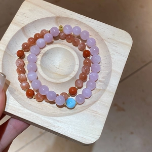 Detailed macro view of double-layer natural stone beaded bracelets in a wooden display tray