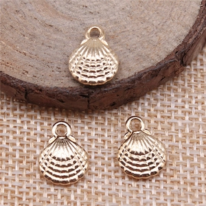 Macro view of three gold alloy shell pendants on a wooden background for jewelry making