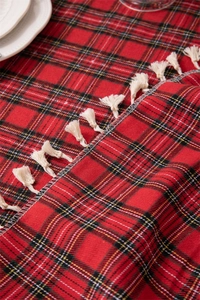 Close-up of red and black checkered cotton-linen tablecloth with creamy white fringe tassels