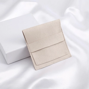 Beige microfiber jewelry pouch with white square gift box on white silk fabric
