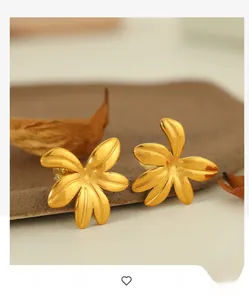Close-up of 18K gold plated 3D flower earrings on a warm autumn-themed ceramic background