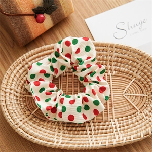 Detail of red and green polka dot bow scrunchie in a wicker basket on a wooden table