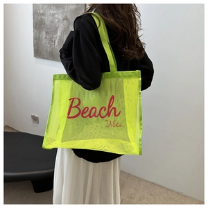 Neon green mesh beach tote bag featuring Beach Vibes print shown on model shoulder
