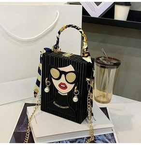 Detail of black box evening bag with cartoon illustration, pearl accent and scarf handle