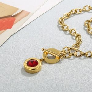 Macro shot of gold thick chain necklace with red gemstone pendant and OT buckle clasp
