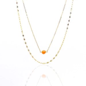 Detail of double-layer gold necklace featuring orange natural stone on white background