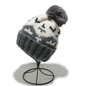 Detail of mohair knit beanie with geometric jacquard pattern and faux fur pompom