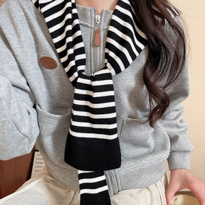 Detail of black and white striped knitted scarf paired with a grey zip-up hoodie