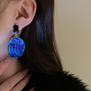 Nahaufnahme von Vintage-Ohrringen mit blau-grünem Emaille-Verlauf am Model