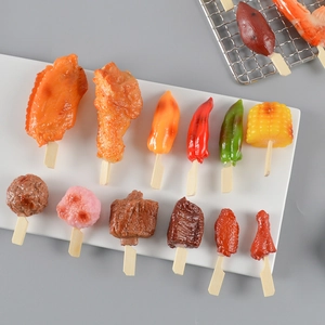 Verschillende realistische PVC BBQ-sleutelhangers met maïs en vleugels op een dienblad