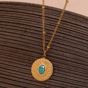 Detailed view of hammered 18K gold plated pendant with blue turquoise on wood background