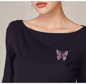 Detail of a sparkling purple butterfly brooch pinned on a black dress worn by a model