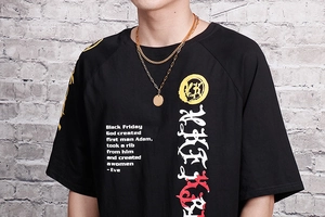Detail of a gold double-layer woven chain necklace worn with a black graphic t-shirt