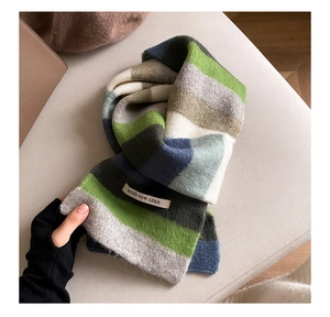Close-up of rainbow striped mohair scarf with a white label on soft fabric texture
