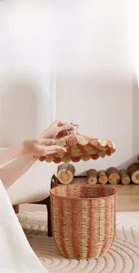 Detail of hand lifting the lid of an orange and straw striped woven storage basket