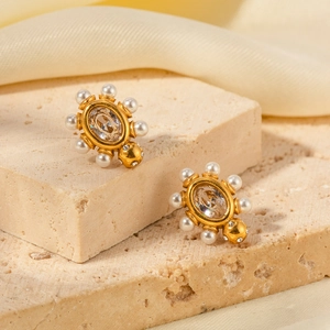 Gros plan détaillé de boucles d'oreilles dorées 18K avec gemme et perles blanches