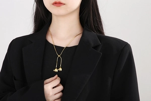 Close-up of a gold-plated snake chain necklace with double elephant pendants on a model