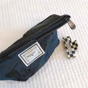 Detail of black floral jacquard makeup bag with TIME TO PARTY label and metal zipper