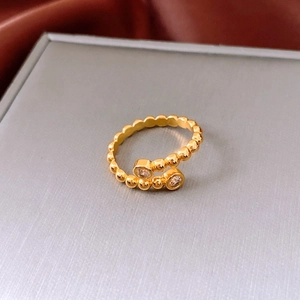 Detail of a gold beaded open ring with sparkling zircons on a grey jewelry box