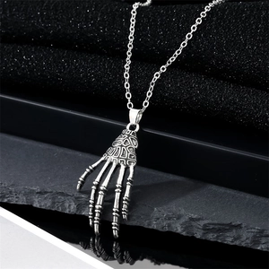 Gothic punk skeleton hand pendant necklace with silver finish on black stone background
