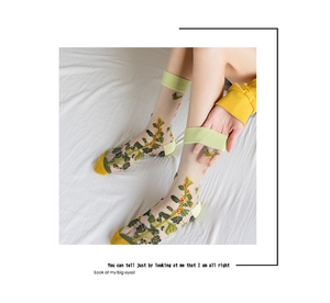 Detail of sheer mesh socks featuring yellow floral embroidery and green cotton trim