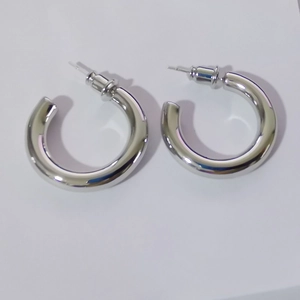 Close-up of minimalist silver metallic thick hoop earrings with clear rubber backs